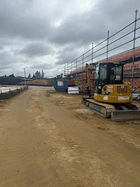 Excavator and earthworks beside the scaffolded building